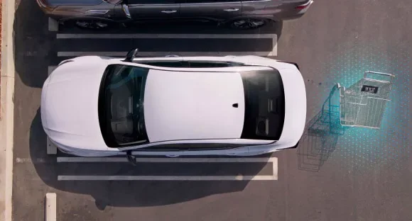 Top view of a white 2027 Nissan Altima in a parking lot with rear sensors detecting a shopping cart behind it at MATZ Nissan in Troy AL